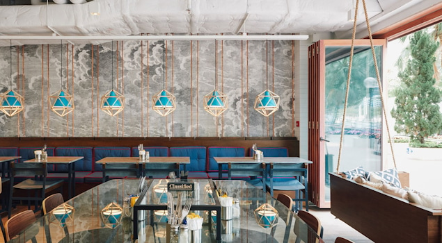 Classified Hong Kong is more than a dining experience; it's an architectural masterpiece that engages all the senses. Our inspiration drew from the café's coastal surroundings, translating into an architectural marvel that embraces marine-blue tiles, rustic timber flooring, and bespoke lobster-pot-inspired ceiling lights. Design by Studio Königshausen.